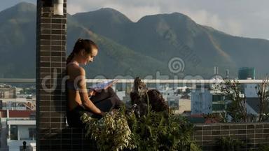 女孩坐在露台屏障上写日记在山上